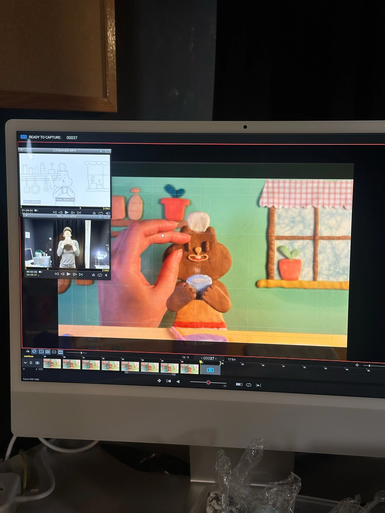 Stop-motion animator's computer screen displaying colourful clay animation sequence of a character in a kitchen set during production of Suuugar!