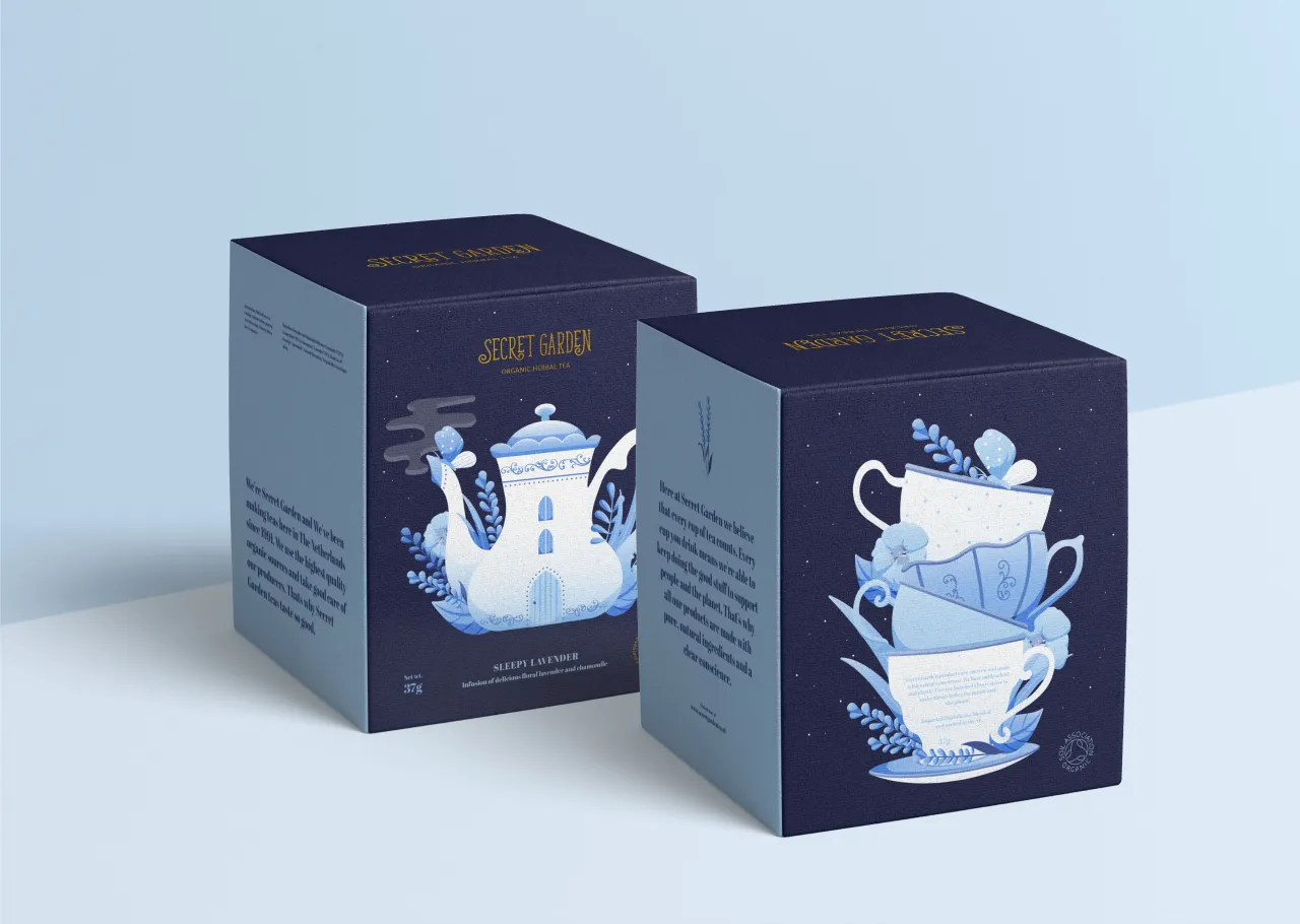 Two navy packaging boxes for Secret Garden tea featuring Noa Maller's illustrations of a teapot-shaped house and stacked teacups with blue floral motifs