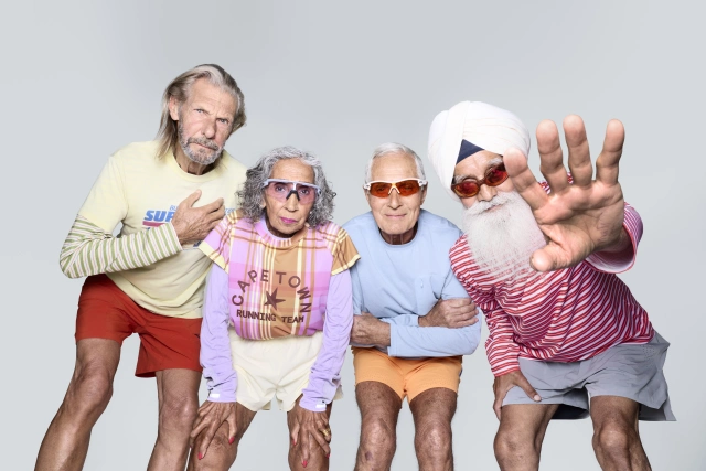 Four older men in colourful casual sportswear pose energetically against a grey background for Rankin's portrait of Altra's Legacy Team running campaign
