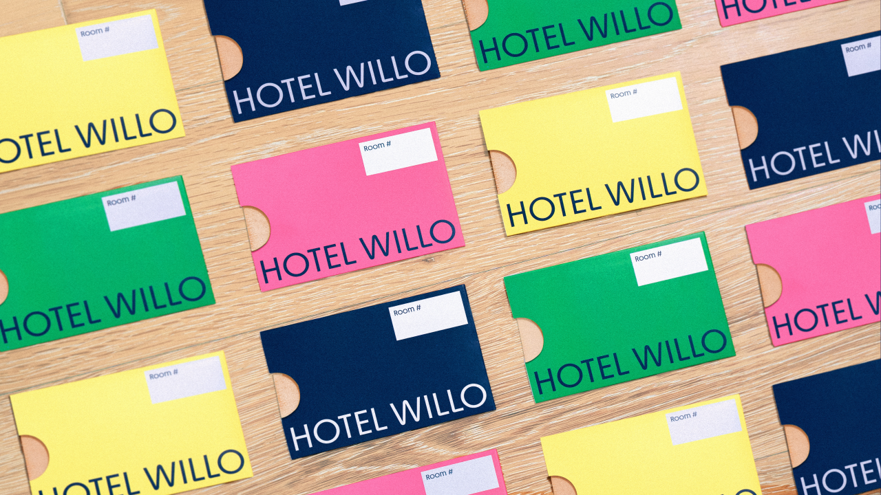 Colourful Hotel Willo key cards in yellow, pink, green and navy blue arranged on a wooden surface