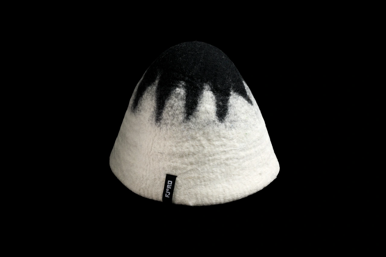 Fjord sauna's wool hat with black top half and cream bottom half, featuring the brand's small label on the side