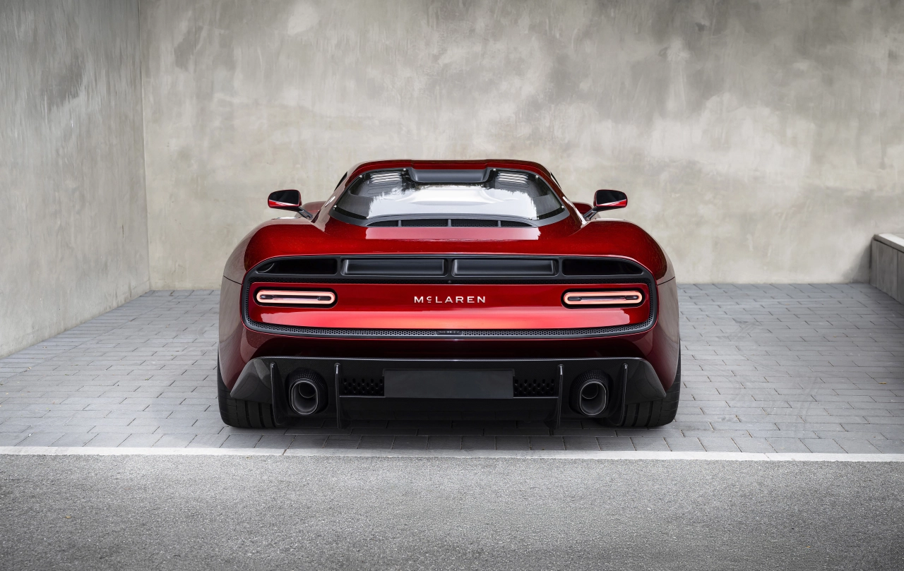 Red McLaren P50 supercar photographed from behind against a concrete wall, displaying the brand's rear badging and dual exhaust outlets
