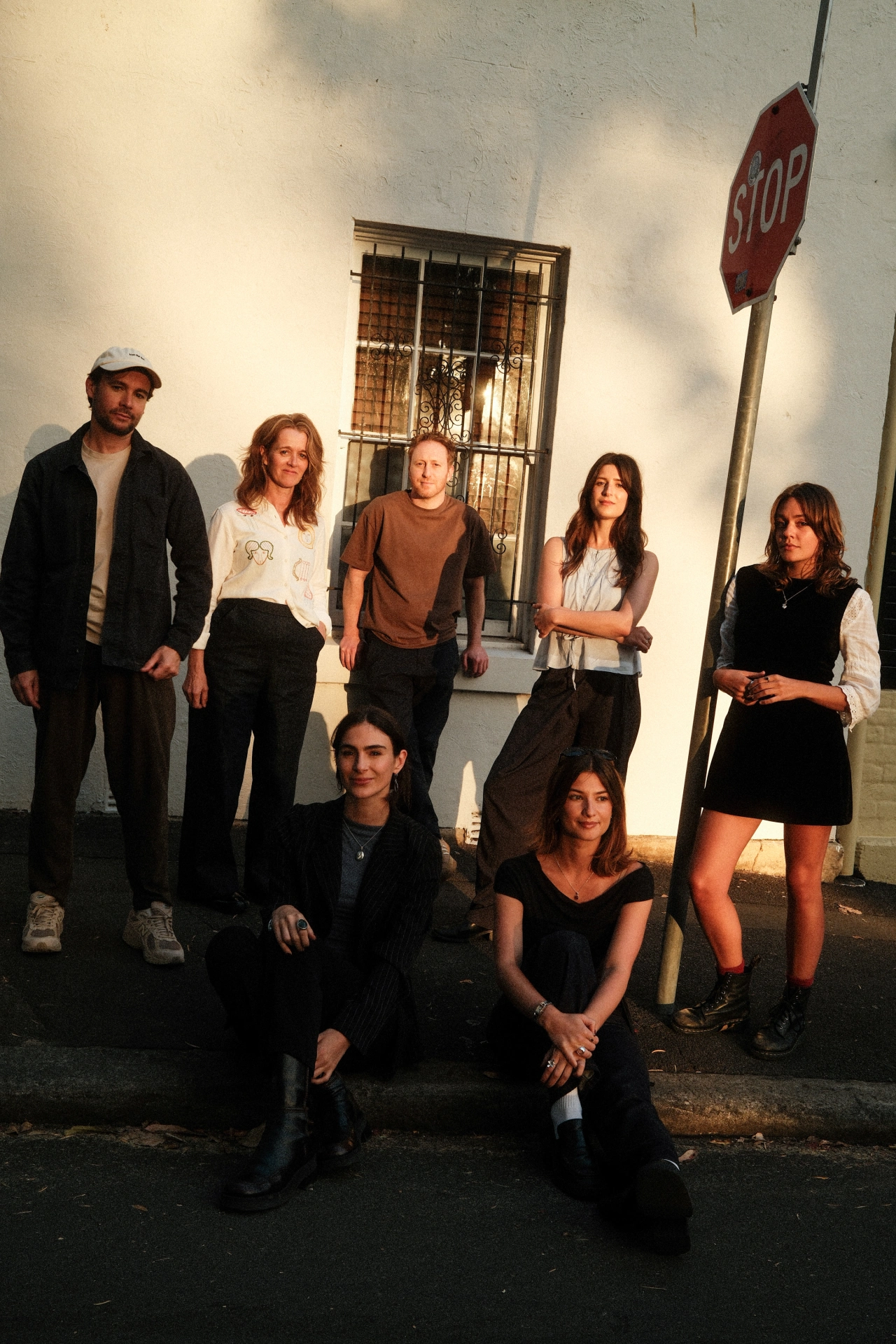 Seven members of the Universal Favourite creative team pose together against a white wall with a barred window and red stop sign beside them