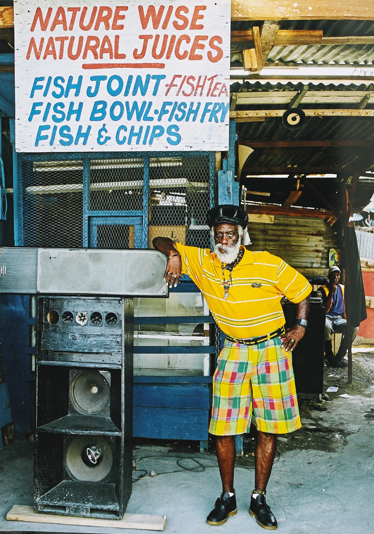 Melbourne James AKA Jah Stitch (deejay name) or Major Stitch (selector name), wearing Desert Boots beside his sound system on Princess Street, downtown Kingston, 2011. Photograph © Mark Read