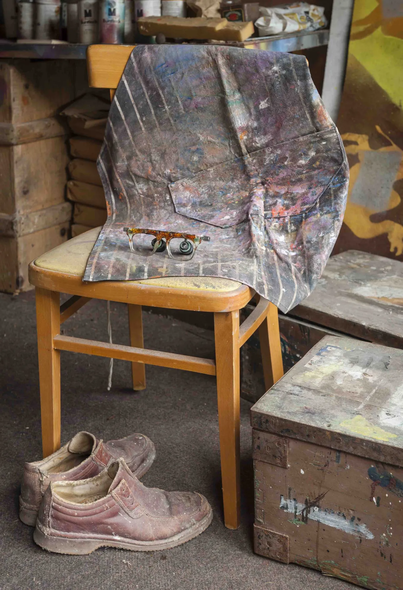 Worn pink shoes sit on the floor beside a wooden chair draped with a paint-stained cloth and art materials in Sidney Nolan's studio at The Rodd