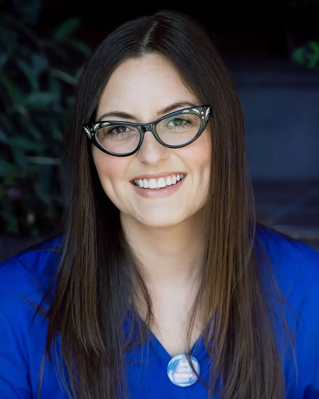 Zoe Hitchen with long dark hair and black-framed glasses wearing a bright blue blazer, smiling at the camera