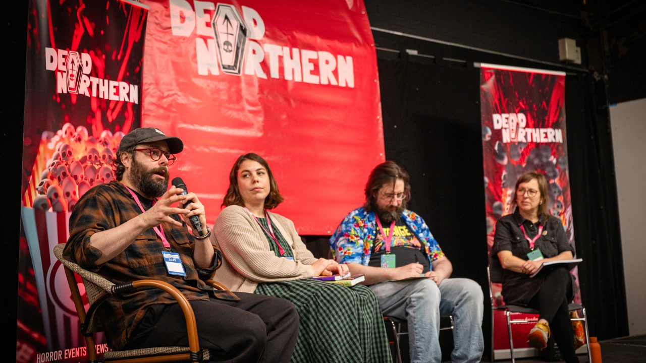 Panel discussion at Thought Bubble festival with four speakers on stage in front of red Dead Northern branding, one holding a microphone