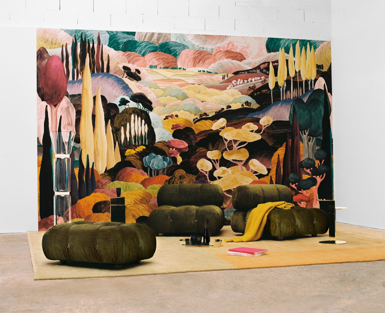 Sarah Martinon's colourful mural installation featuring stylised landscape with rolling hills, trees and fields, with sculptural fabric forms arranged in front on a wooden platform