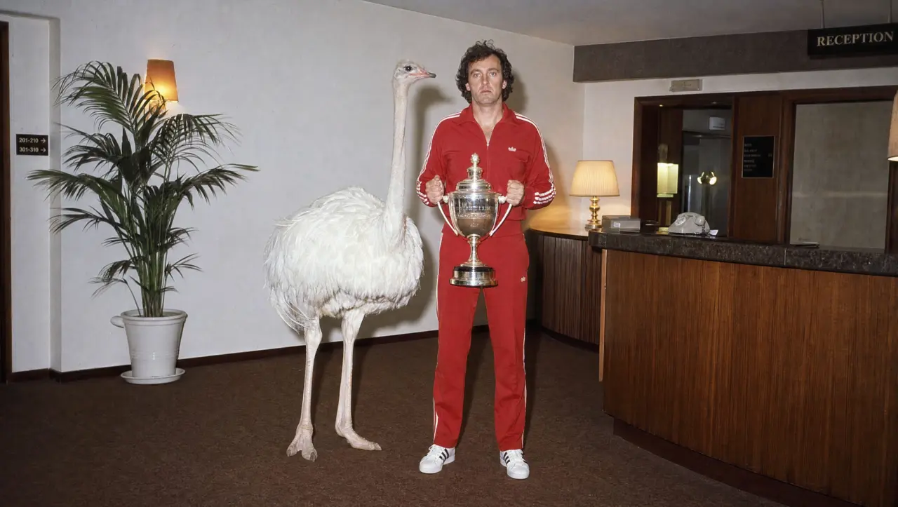 Person in red clothing holding a trophy stands next to a large white emu in a hotel reception area