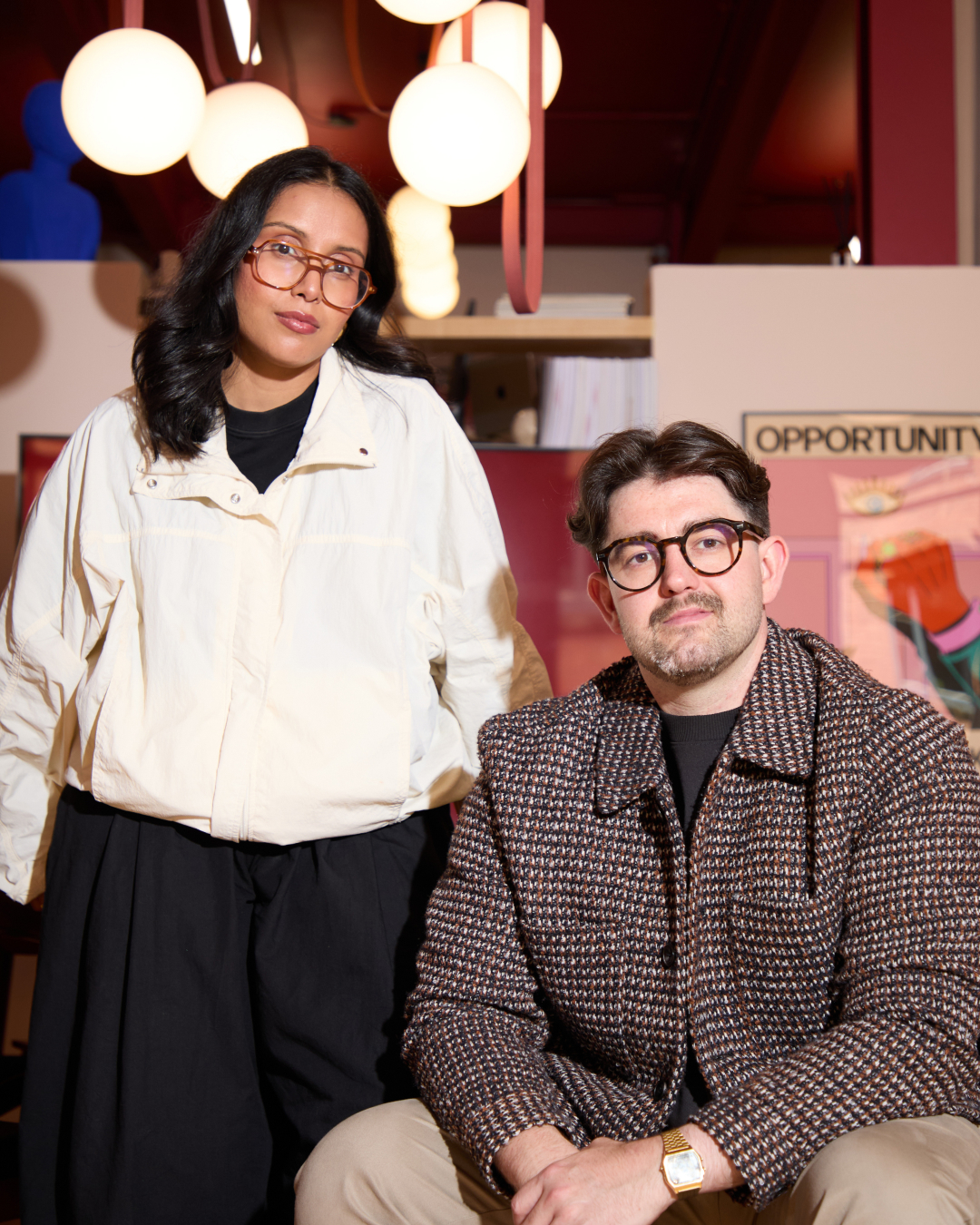Poonam Saini Kilb and Matt Kilb, co-founders of Kiss Branding, seated together in their Leeds studio beneath illuminated pendant lights