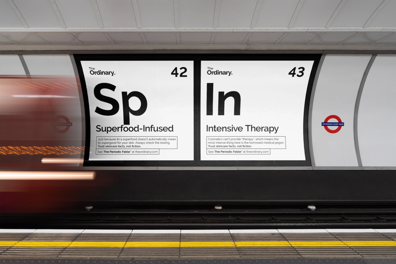 Two parody periodic table element panels on a London Underground train displaying "Sp - Superfood-Infused" and "In - Intensive Therapy", mocking beauty industry buzzwords