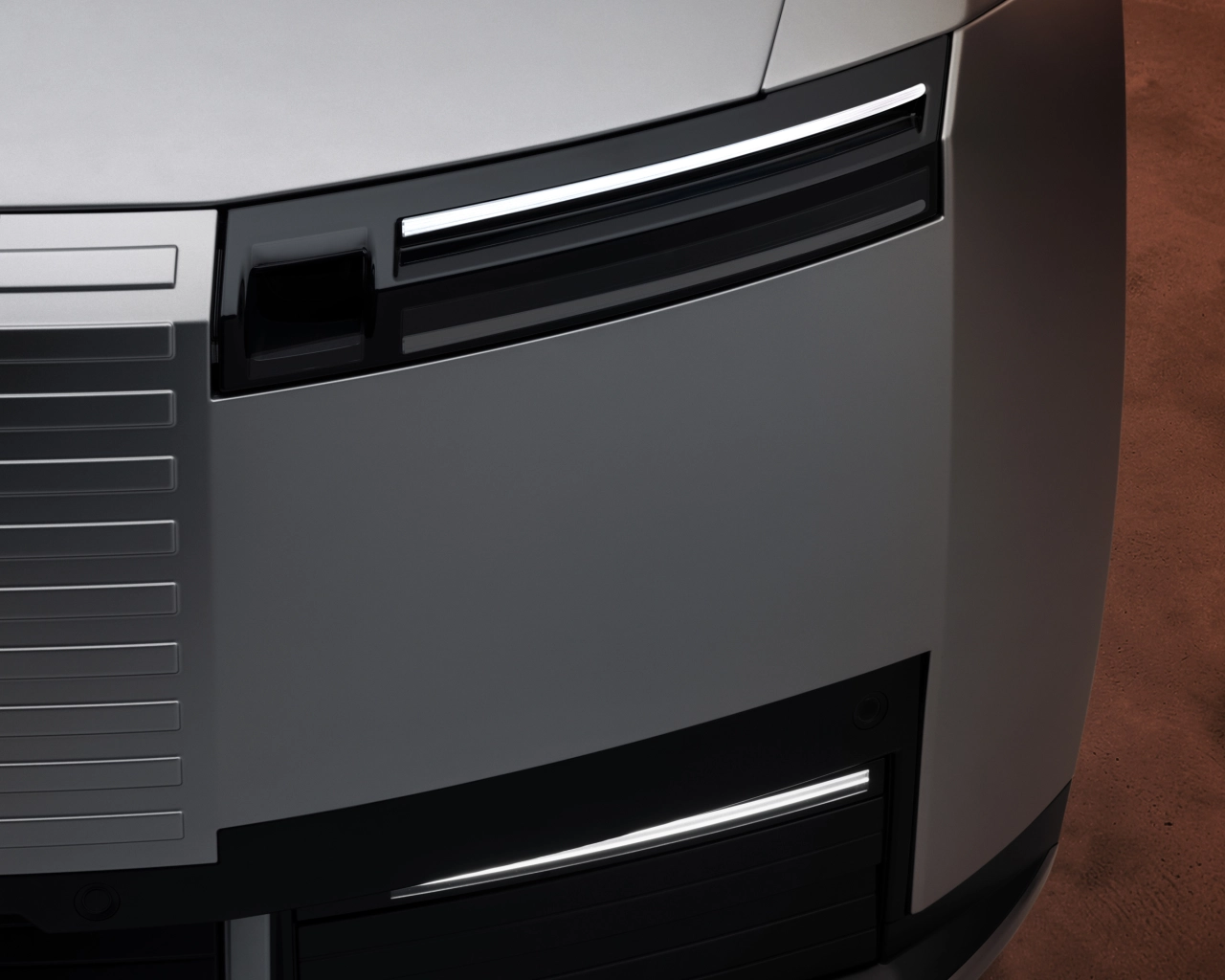 Close-up detail of the Jaguar Type 01's angular headlight design with illuminated LED strip on grey bodywork