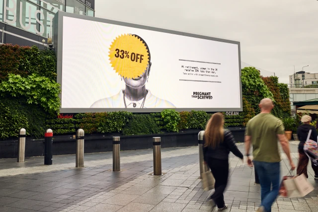 Large outdoor advertisement featuring a person's head obscured by a yellow starburst badge reading "33% OFF", with Pregnant Then Screwed branding, displayed on a city street billboard