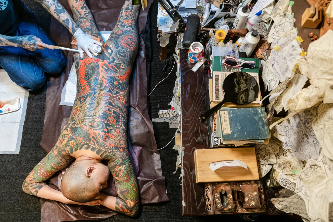 Tattoo artist Hori Momo works on his client by using the tebori technique (stick and poke by hand) tattoos, Tebori is the Japanese traditional method of tattooing performed with a thin piece of bamboo, a nomi. Needles are attached to the nomi. Meguro City, Tokyo