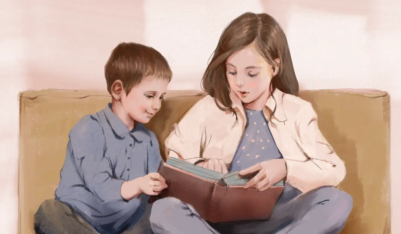 Two children sit together on a sofa sharing a book, the older girl reading aloud to the younger boy.