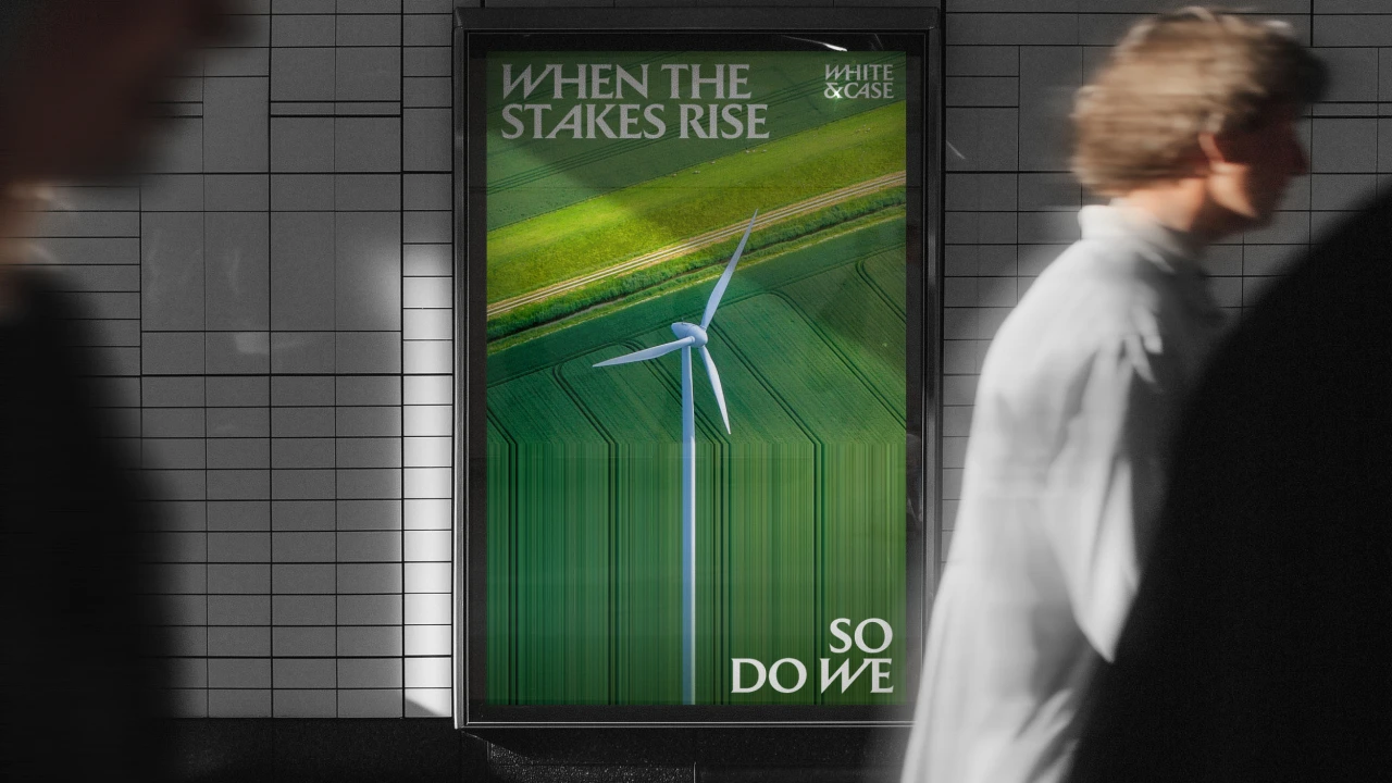 Poster on underground platform with wind turbine and green fields above text "When the stakes rise" and "So do we" in White & Case rebrand