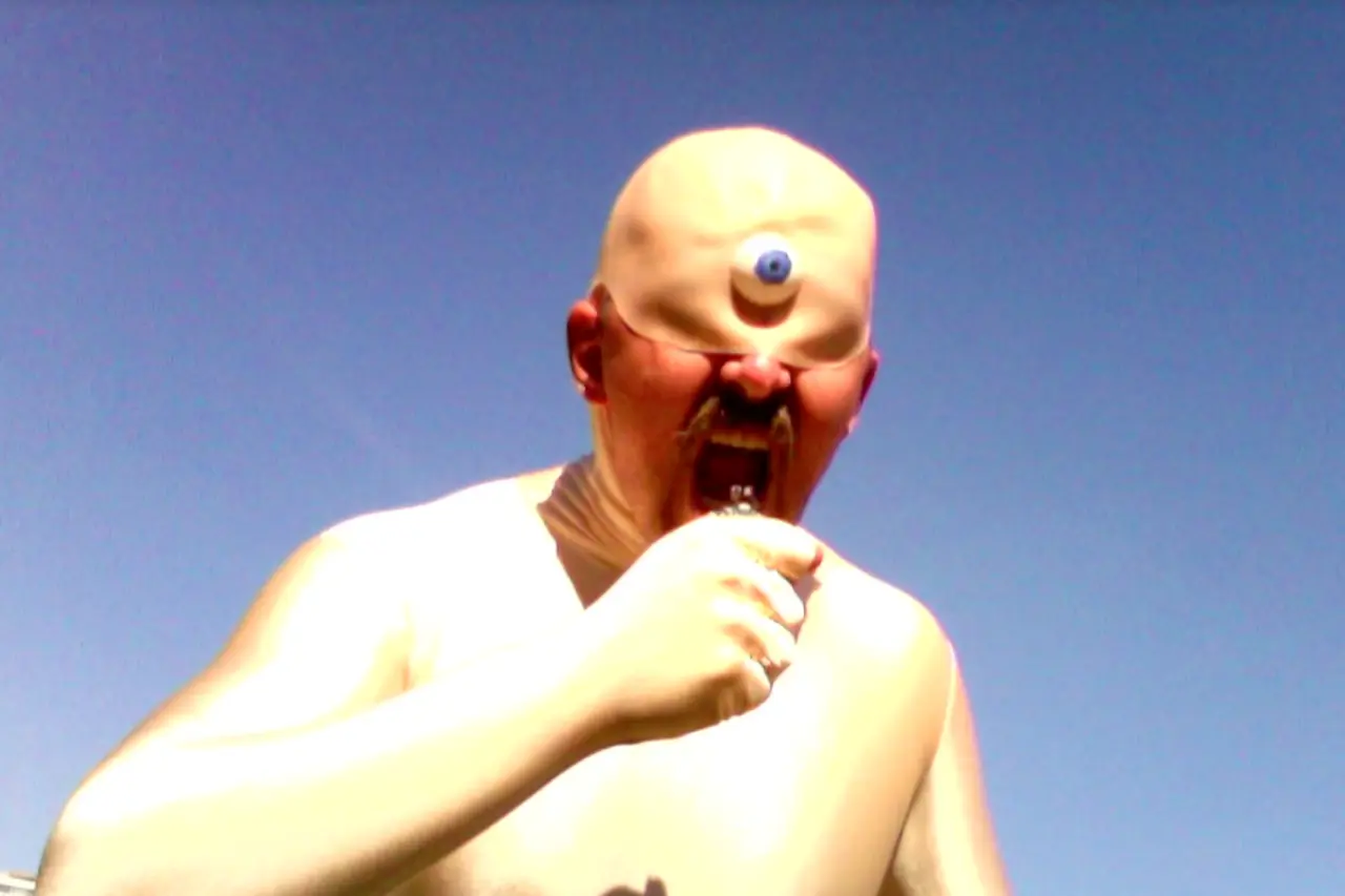 Cream-coloured figure with exaggerated facial features and open mouth against a clear blue sky, from a scene in the iMac-powered film remake of The Odyssey