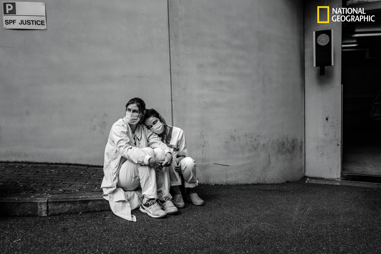 Taking a brief break during ceaseless frontline work treating patients with the coronavirus, nurses Caroline Quinet (at left) and Yasmina Cheroual rest outside CHU Ambroise Paré hospital. The pair, who had known each other for only a few months, pulled long shifts in the intensive care unit. Like many medical facilities around the world, Belgian hospitals initially were overwhelmed by a rush of patients with the virulent, ever changing new disease. These nurses, pulled from their standard duties, were thrown into full-time COVID-19 work—reinforcement troops for a long, exhausting battle. (Cédric Gerbehaye/National Geographic)