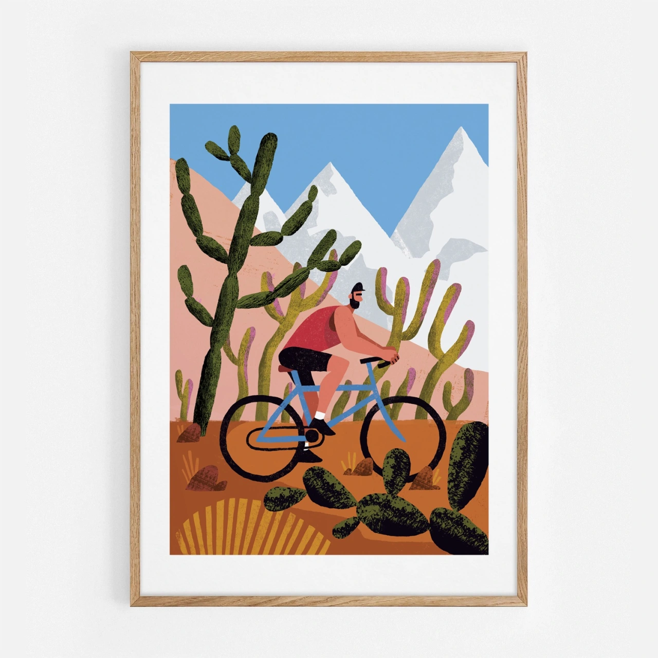 Person cycling through desert landscape with tall cacti and snow-capped mountains in the background, framed in natural wood