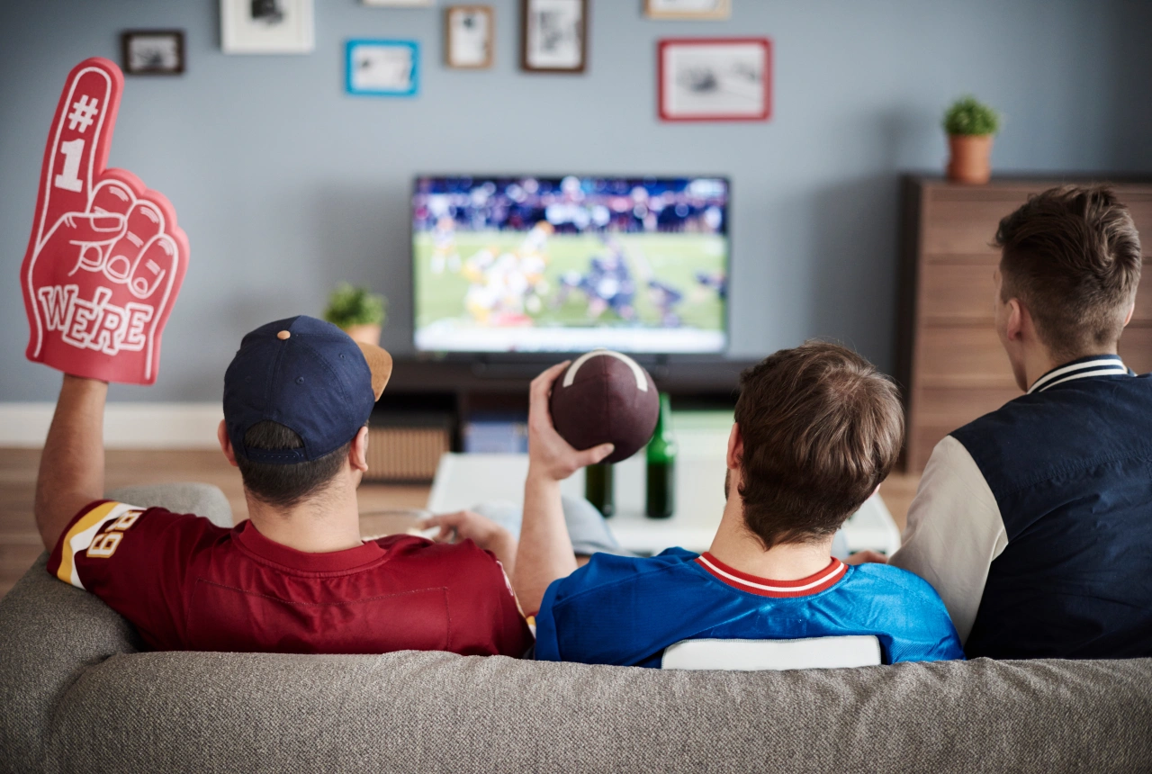 Four people sitting on a sofa watching American football on a television, with one holding a foam finger and another holding a football The government is expanding its presence in the Indo-Pacific and raising its military profile there amid rising Chinese