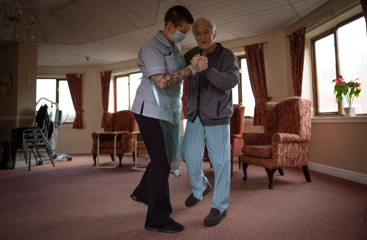 Jack Dodsley, 70, dances with a carer in PPE © Tom Maddick / SWNS