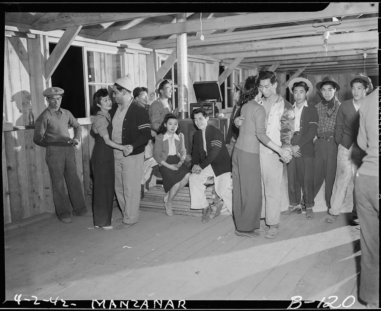 Japanese American detainees gather inside a wooden barrack structure at Manzanar internment camp in the 1940s