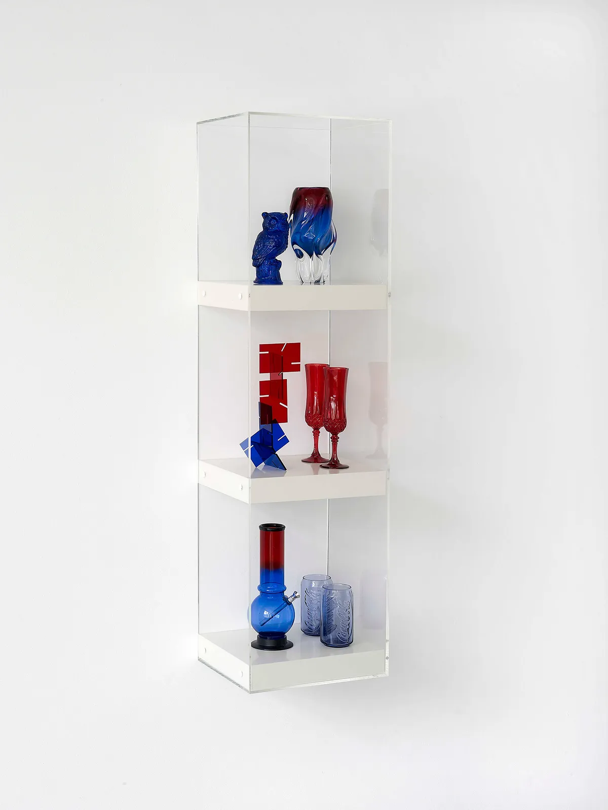 Matthew Darbyshire Untitled: Shelves No. 7 (Series 2) 2010 Resin cast owl figurine, Murano vase, acrylic desk sculpture, crystal d’arque champagne flutes, acrylic bong, McDonald’s Coca Cola glasses, shelves, Perspex case 120 × 30 × 30 cm Courtesy of the artist and Herald St, London