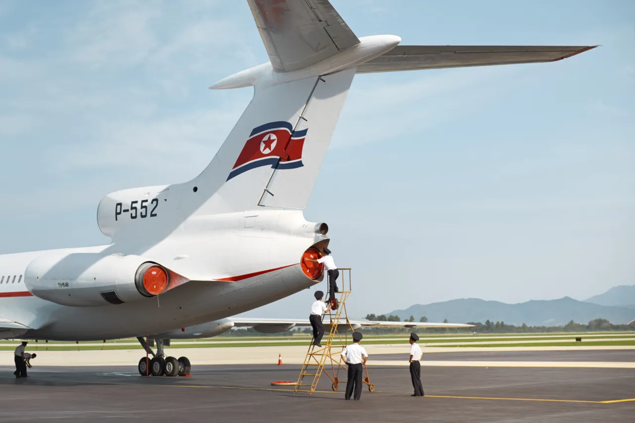 Pilots secure cover to the engines of a Tupolev-154 after a flight from Sunan to Kalma