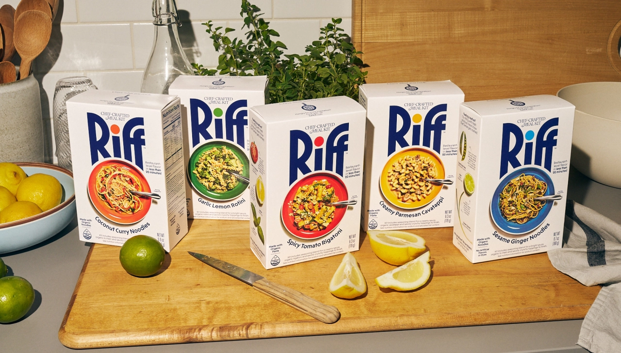 Five Riff meal kit boxes arranged on a wooden board with limes, lemon slices and fresh herbs, displaying different recipes with vibrant dish photography on their packaging