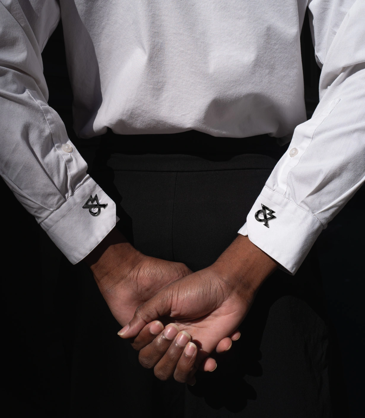 Two people in formal shirts with White & Case cufflinks shake hands against a black background