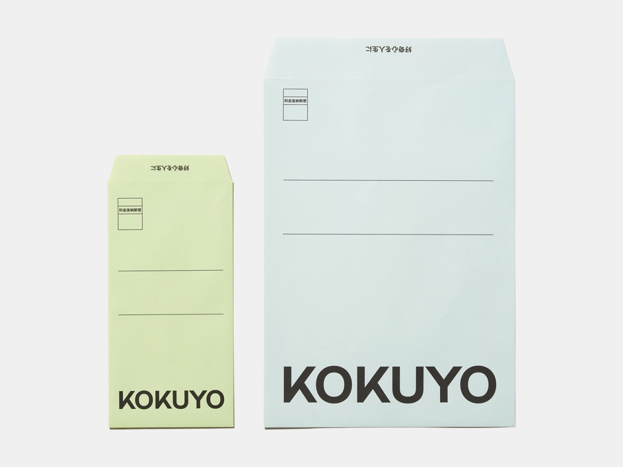 Two Kokuyo notepads in pale yellow-green and pale blue with the brand name printed at the bottom and lined writing spaces above