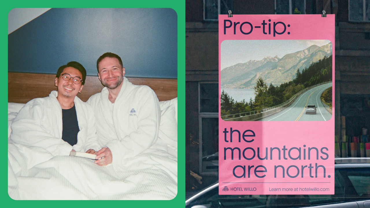 Two men in white robes sitting together on a bed next to a pink poster reading "Pro-tip: the mountains are north" with a road and mountain landscape image