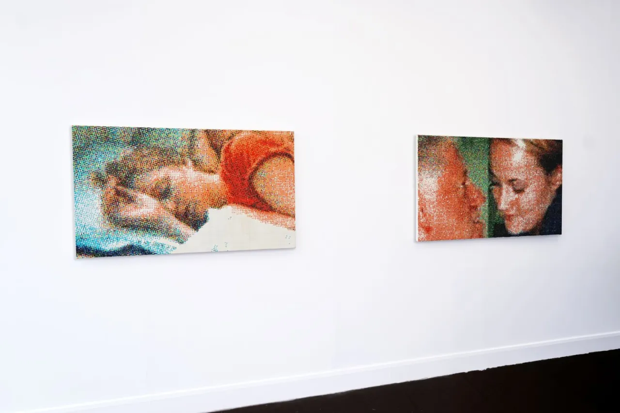Two pixelated paintings by Lily Bunney hung on a white gallery wall, each composed of coloured square grids that form figurative images when viewed from a distance
