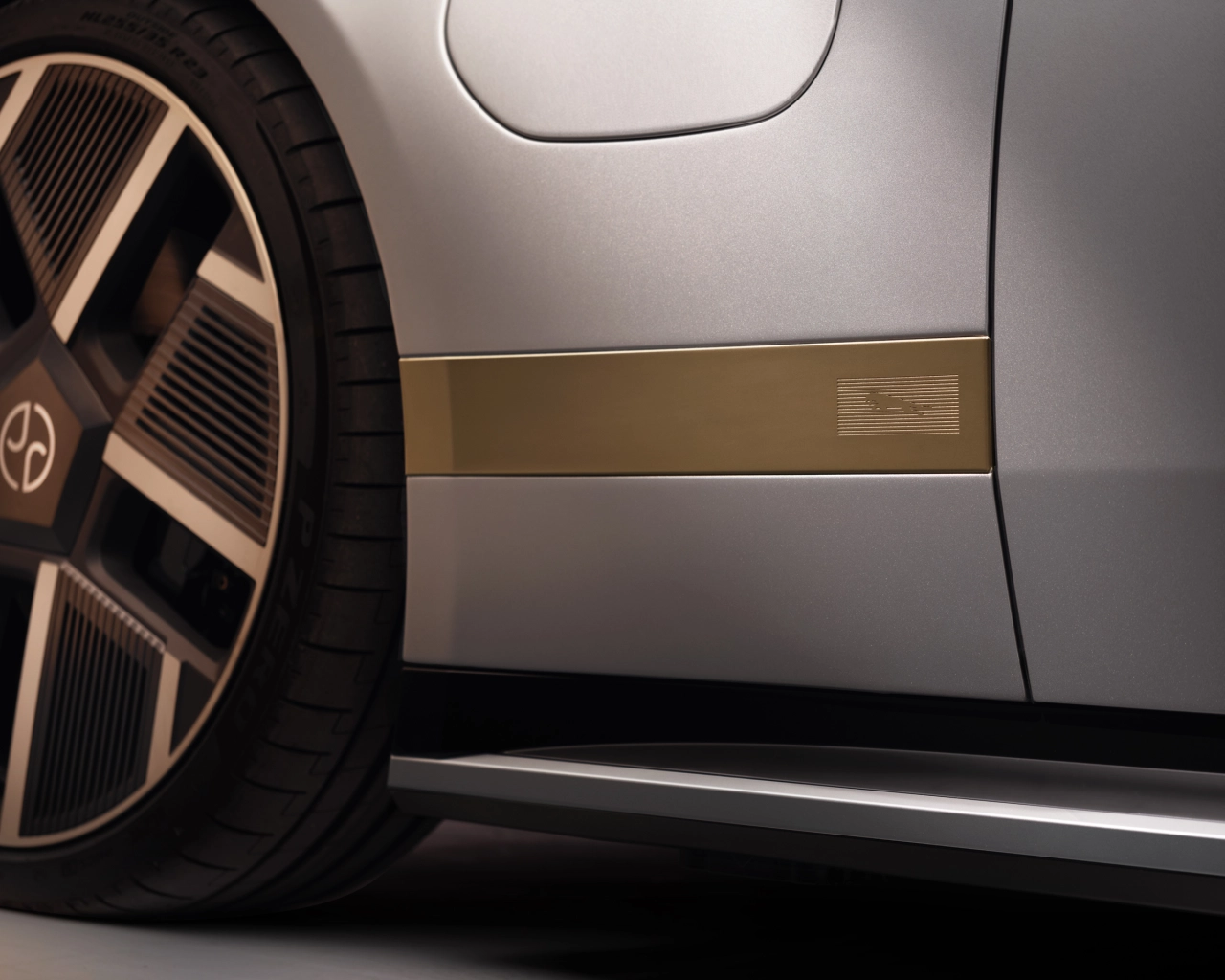 Close-up detail of silver Jaguar Type 01 showing bronze-trimmed side panel, black wheel rim and lower bodywork line