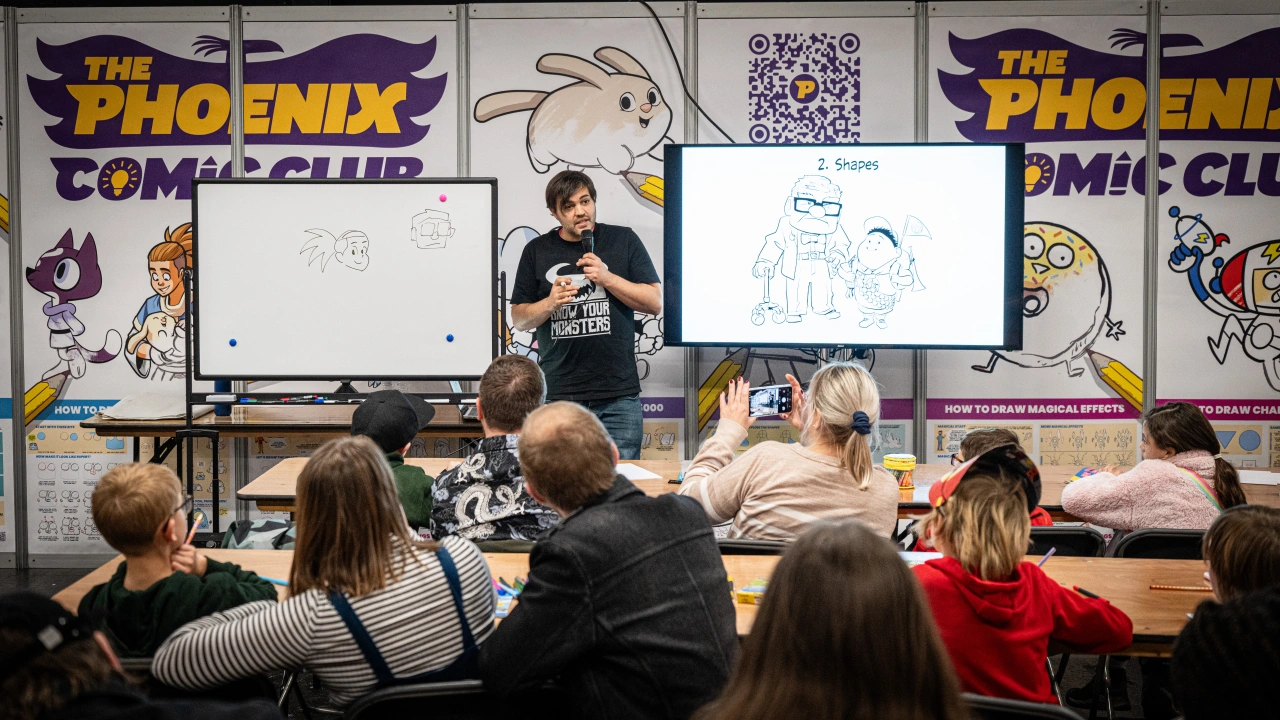 Artist demonstrating comic drawing techniques to an audience seated at The Phoenix Comic Club event