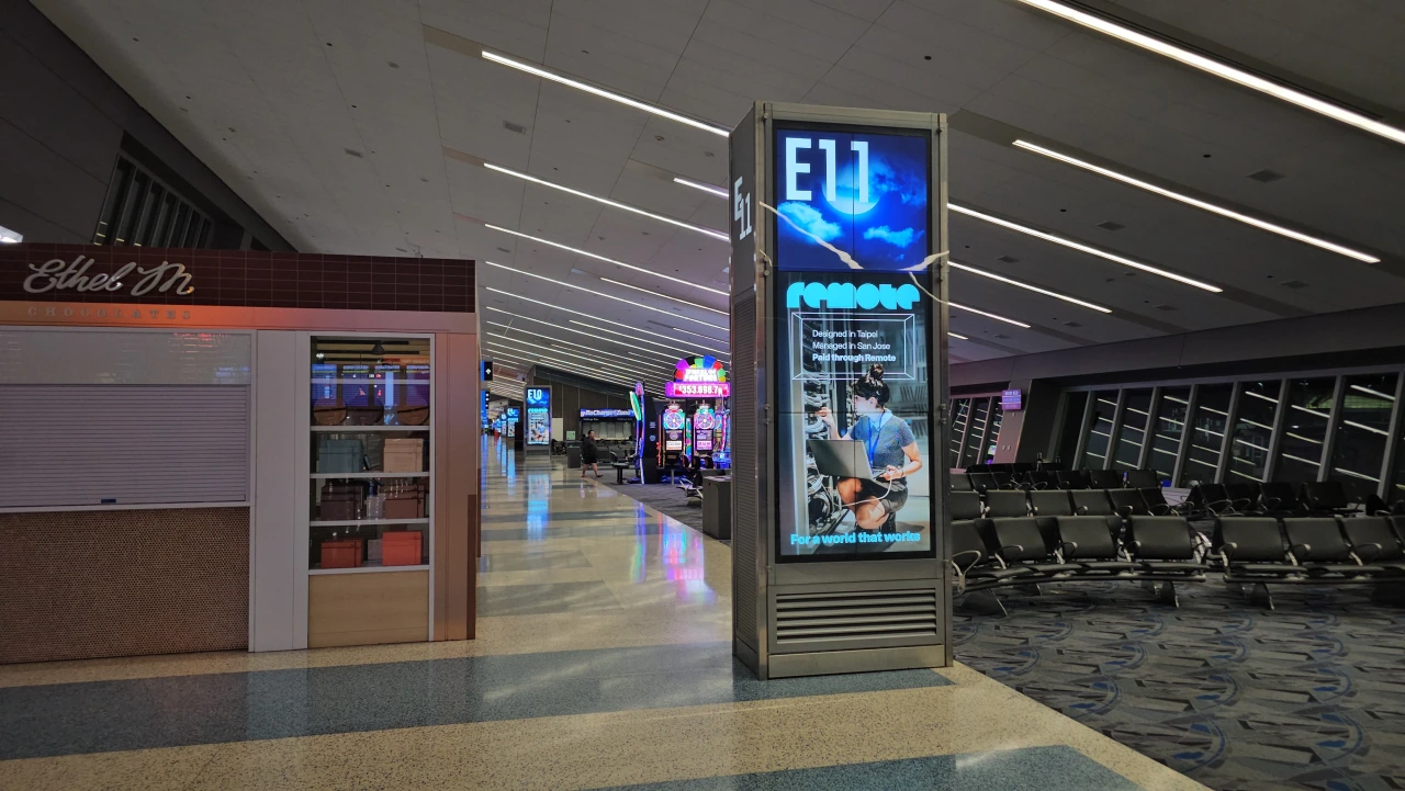 Digital pylon display in a modern airport or transit terminal showing the EU branding in blue light among other signage and seating areas