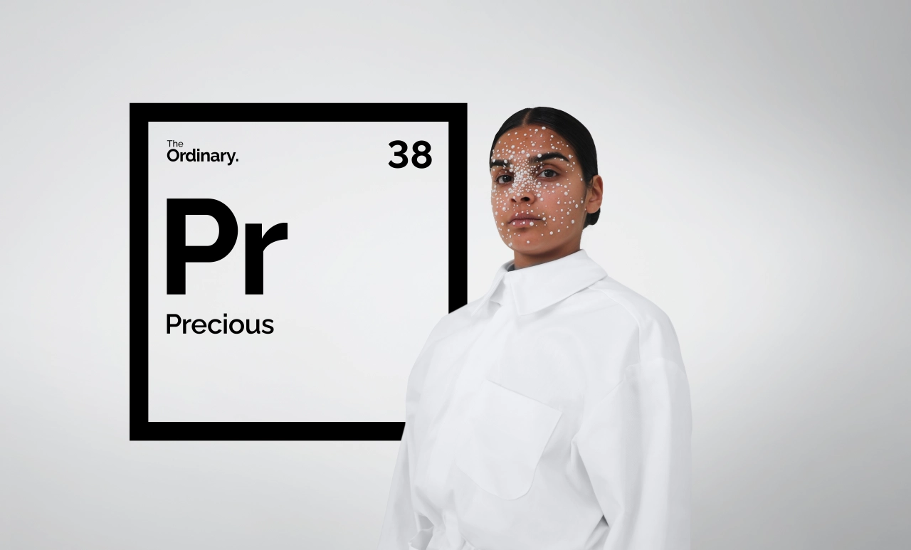 Person in white shirt next to periodic table element square showing "Pr" for Precious with number 38, part of Uncommon's parody campaign