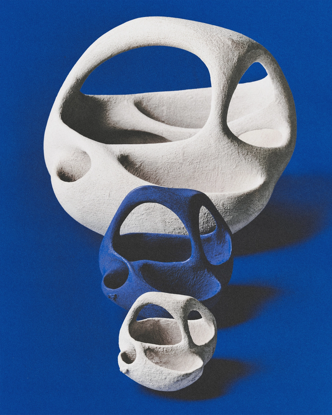 White, blue and grey abstract sculptural forms with organic cutout shapes stacked vertically against a blue background