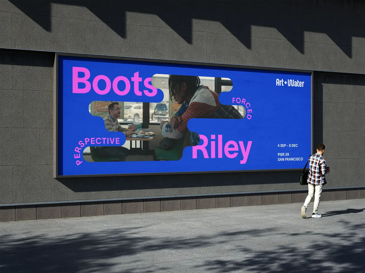 Blue billboard for Art + Water featuring photography of people and the names Boots and Riley, with geometric shapes and text on a waterfront building