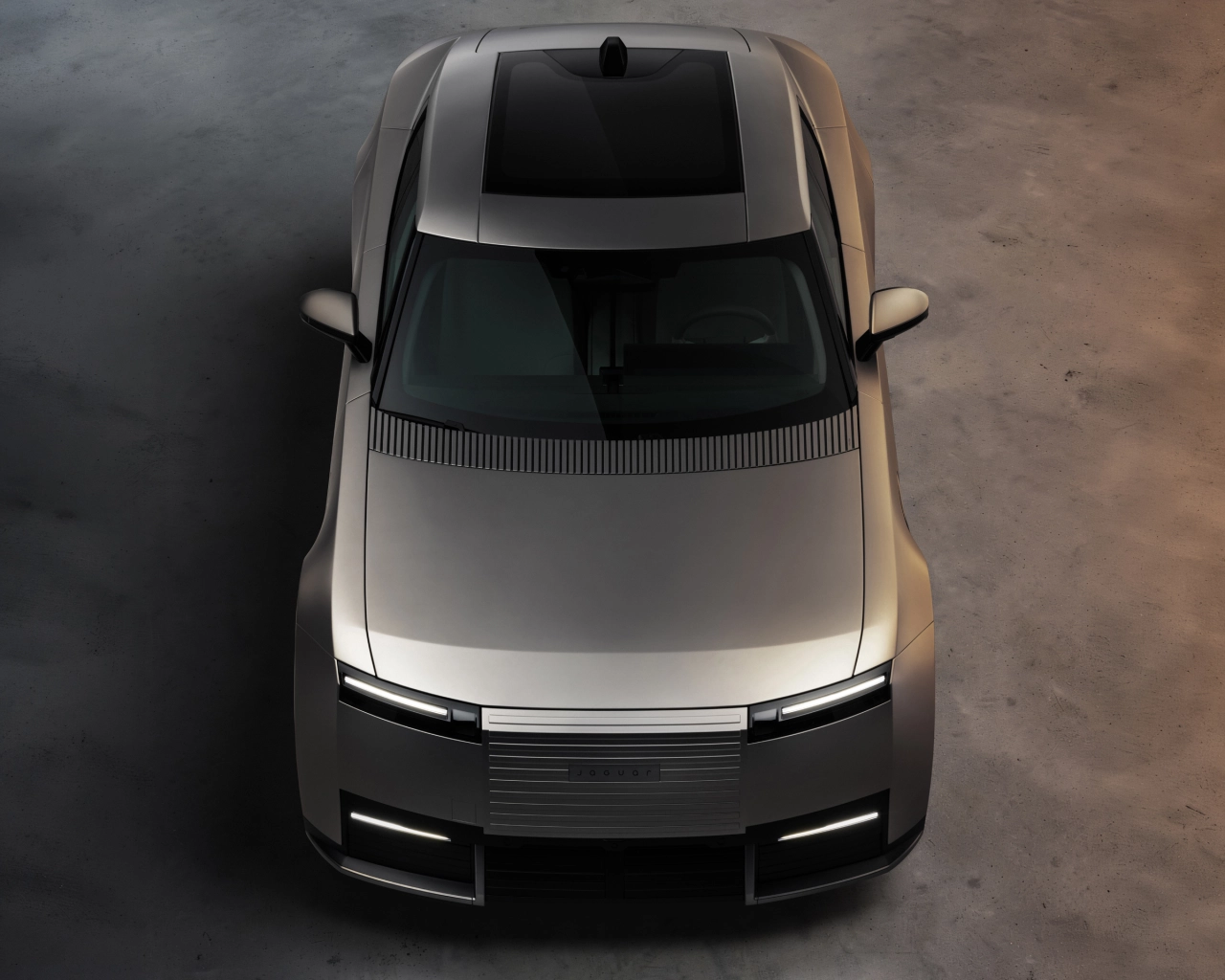 Overhead view of the silver Jaguar Type 01 production car with its distinctive horizontal LED light bar and sleek bonnet design