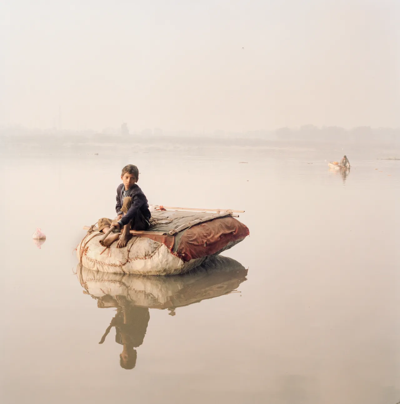 A homeless boy fishes for coins using a string and a magnet along the Yamuna river, one of the main tributaries of the Ganges, 2015 © Giulio Di Sturco