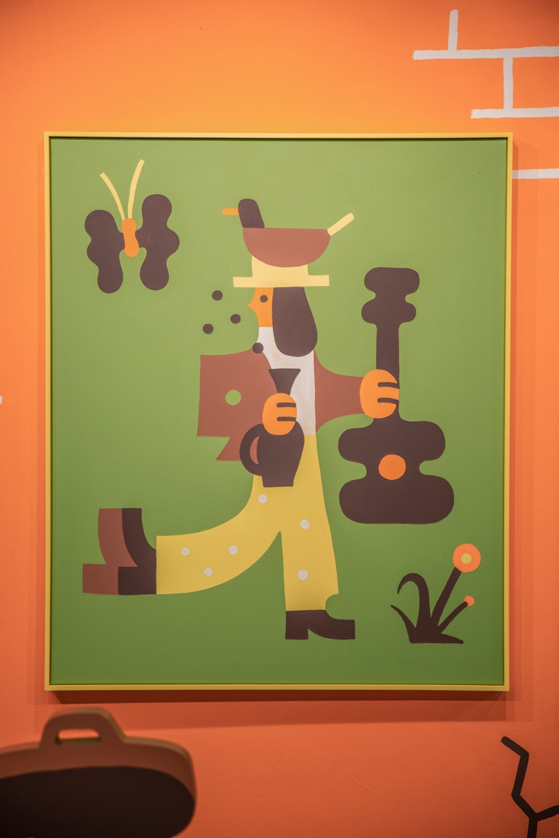 Geometric illustration of a stylised figure juggling abstract shapes in brown, orange and yellow on a green background, part of Philip Lindeman's Sofia exhibition