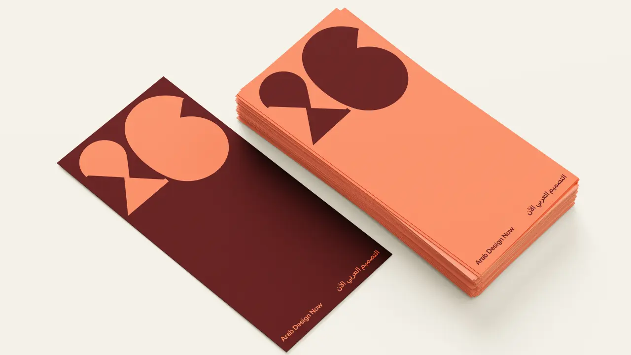 Two folded brochures displaying Pentagram's Design Doha Biennial 2026 identity, featuring geometric shapes in coral and burgundy with interwoven Arabic and English typography
