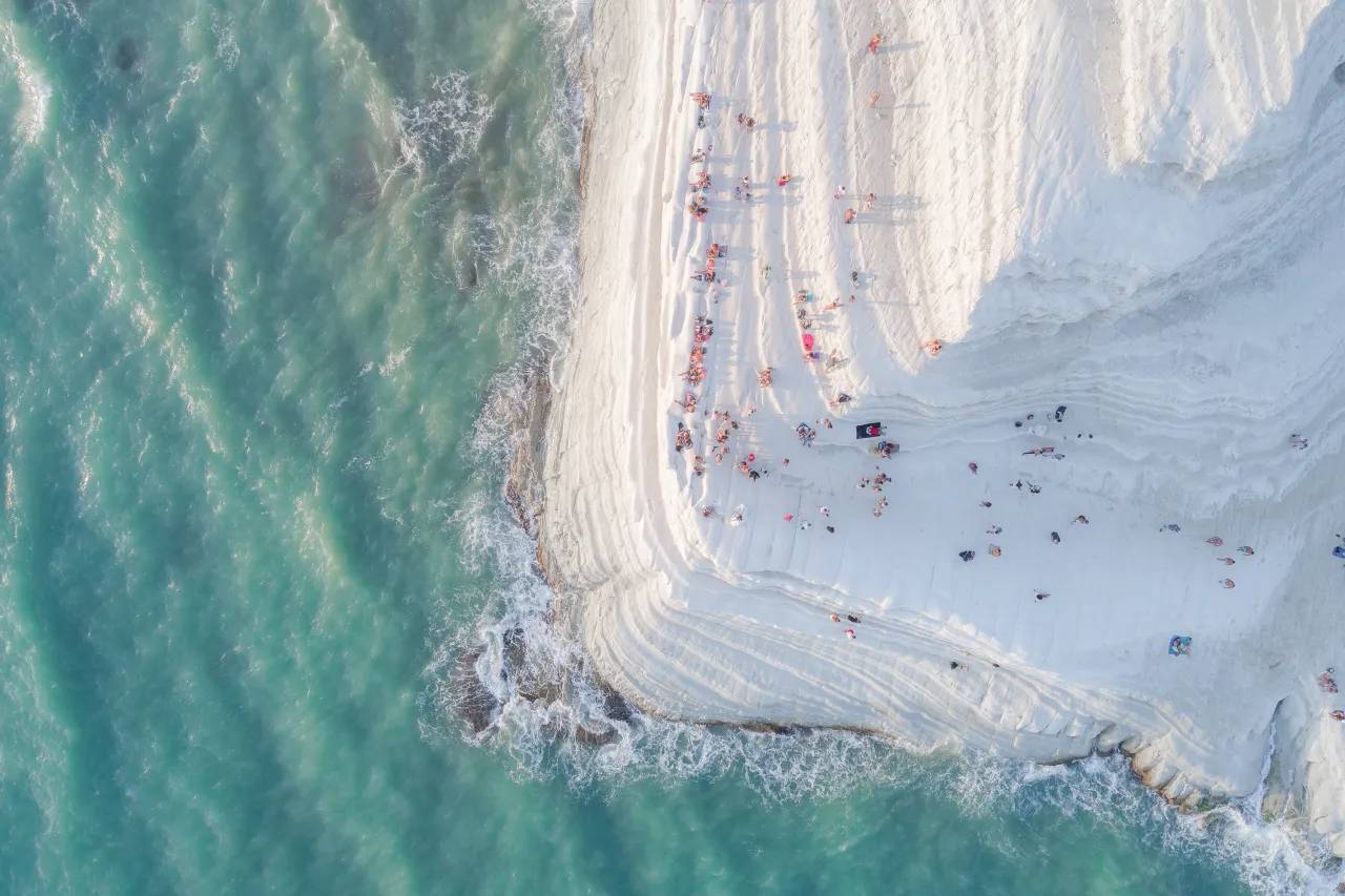 "Scala dei Turchi" (The Turkish Steps) is a white cliff in Realmonte (Sicily) made of a soft limestone and a blinding white marl. Natural erosion has created steps on the cliff face, making it look soft and sinuous, like a Big Meringue covered with sprinkles (the people sitting and walking on it). Only after shooting this image, while watching it on a bigger screen, I noticed a newlywed couple in the frame kissing for their wedding photoshoot. Exactly at the edge of the cliff.  Copyright: © Placido Faranda, Italy, Shortlist, Open, Landscape & Nature (2018 Open competition), 2018 Sony World Photography Awards