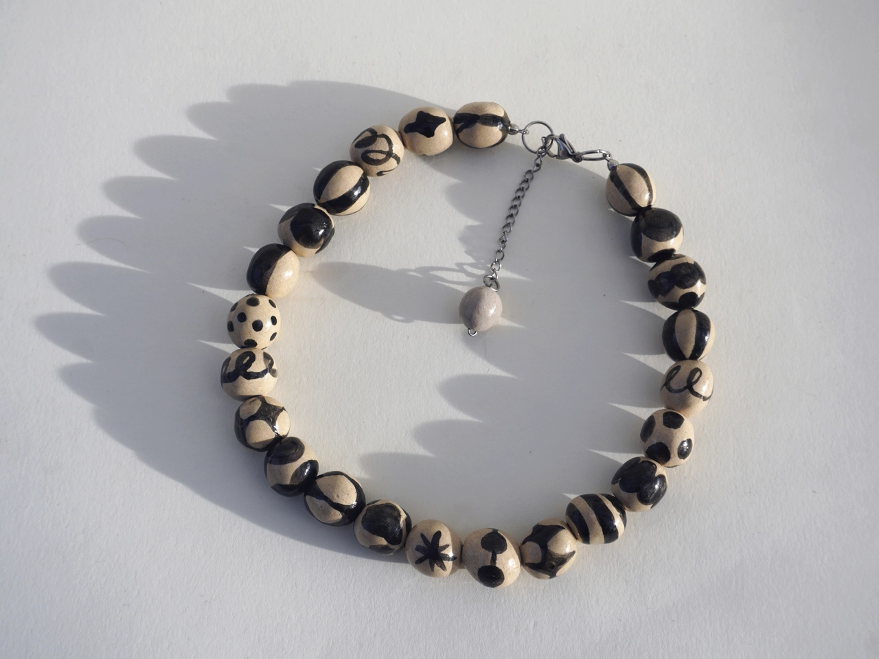 Beaded bracelet with black and cream striped and patterned round wooden beads connected by silver chain link
