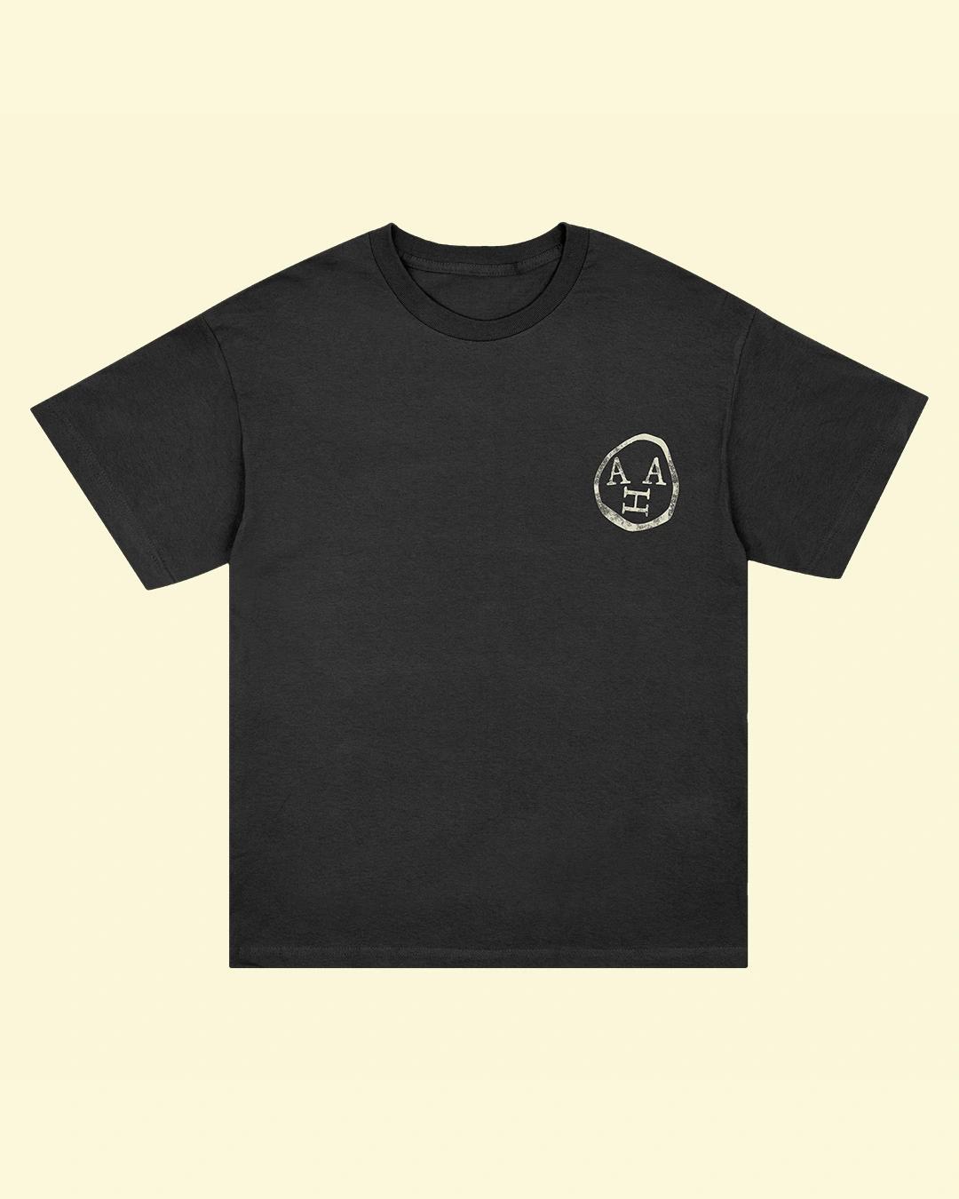 Black t-shirt with white circular logo featuring stylised letters on the chest against a cream background