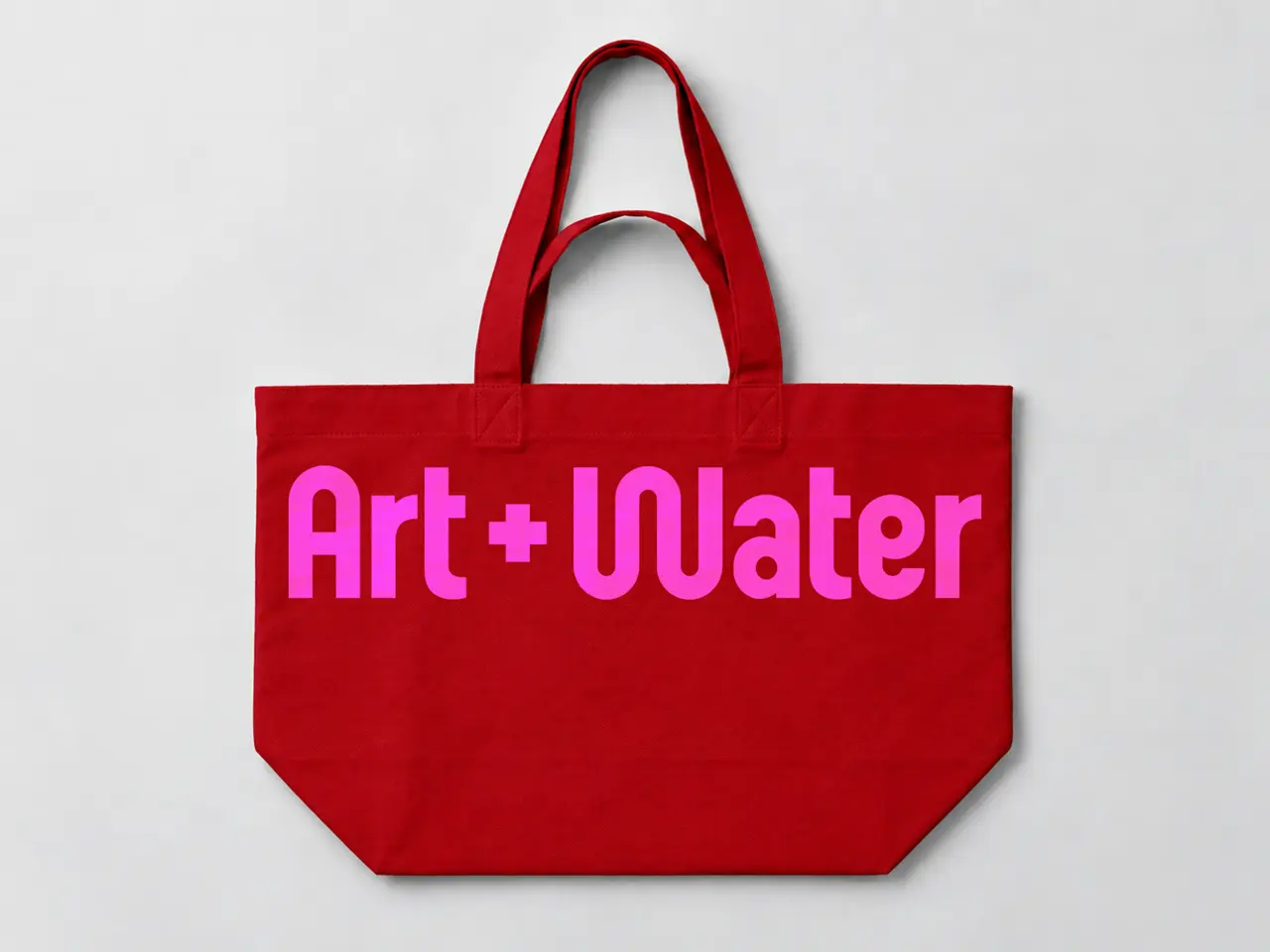 Red tote bag with magenta Art + Water logo printed on front and red handles