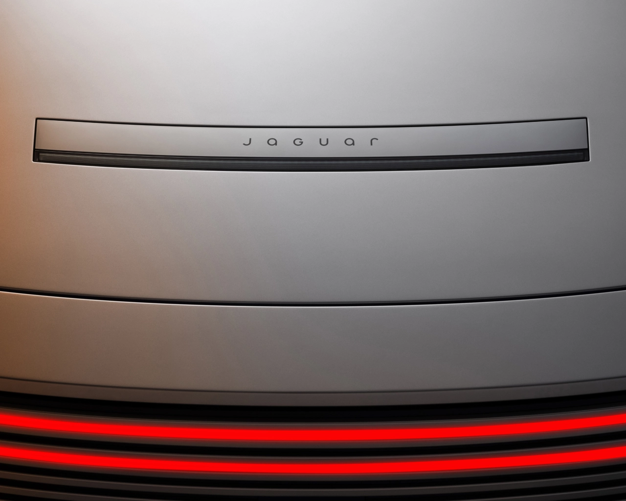 Close-up of Jaguar wordmark on silver trim above illuminated red tail lights on the new Type 01