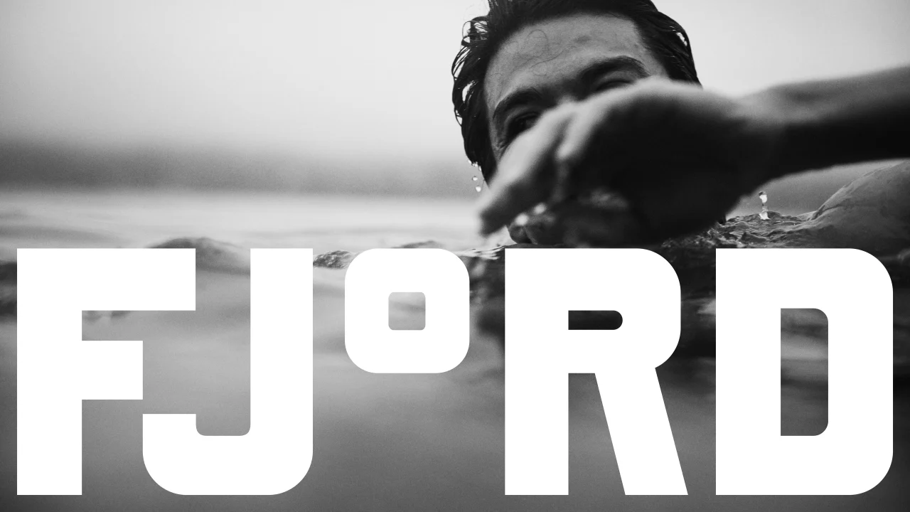 Black and white photograph of a person in water with arm extended, overlaid with large white "FJORD" typography