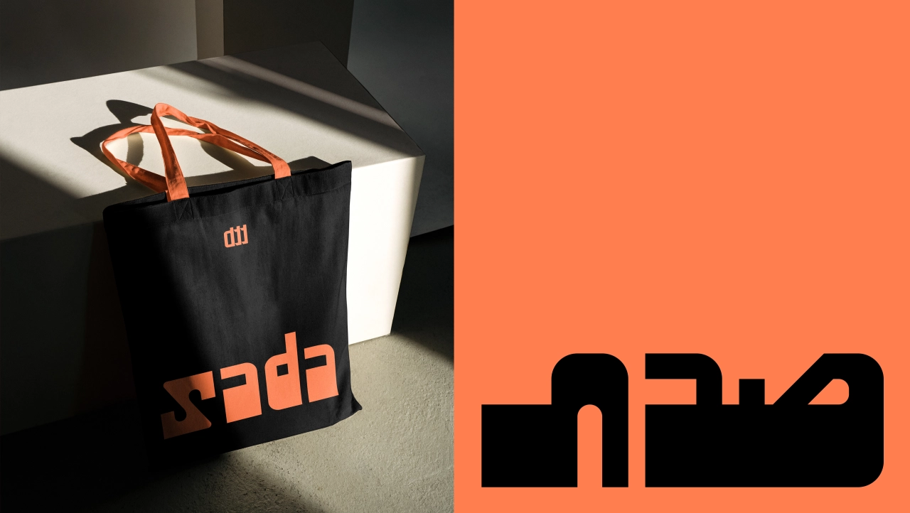 Black carrier bag with orange handles and Sada branding, displayed on a white surface in studio lighting